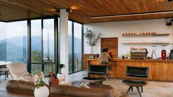 Un interior moderno con techo de madera, una zona de bar y un área de estar con vistas a las montañas.
