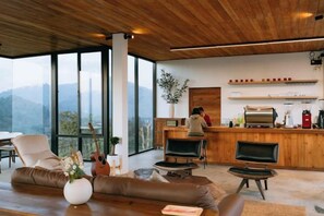 A modern interior with a wooden ceiling, a bar area, and a seating area with a view of the mountains. - Akano Doichang (Mae Suai)