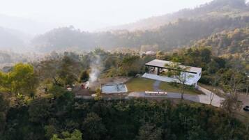 Un edificio moderno con techo plano y un espacio exterior cubierto, rodeado de un bosque denso.
