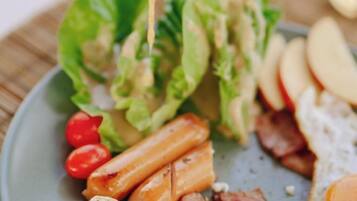 A plate with a salad, bacon, and apple slices.