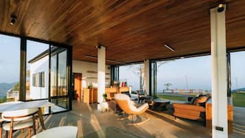 Un espacio habitable de concepto abierto con techo de madera, ventanas amplias y vistas al exterior.
