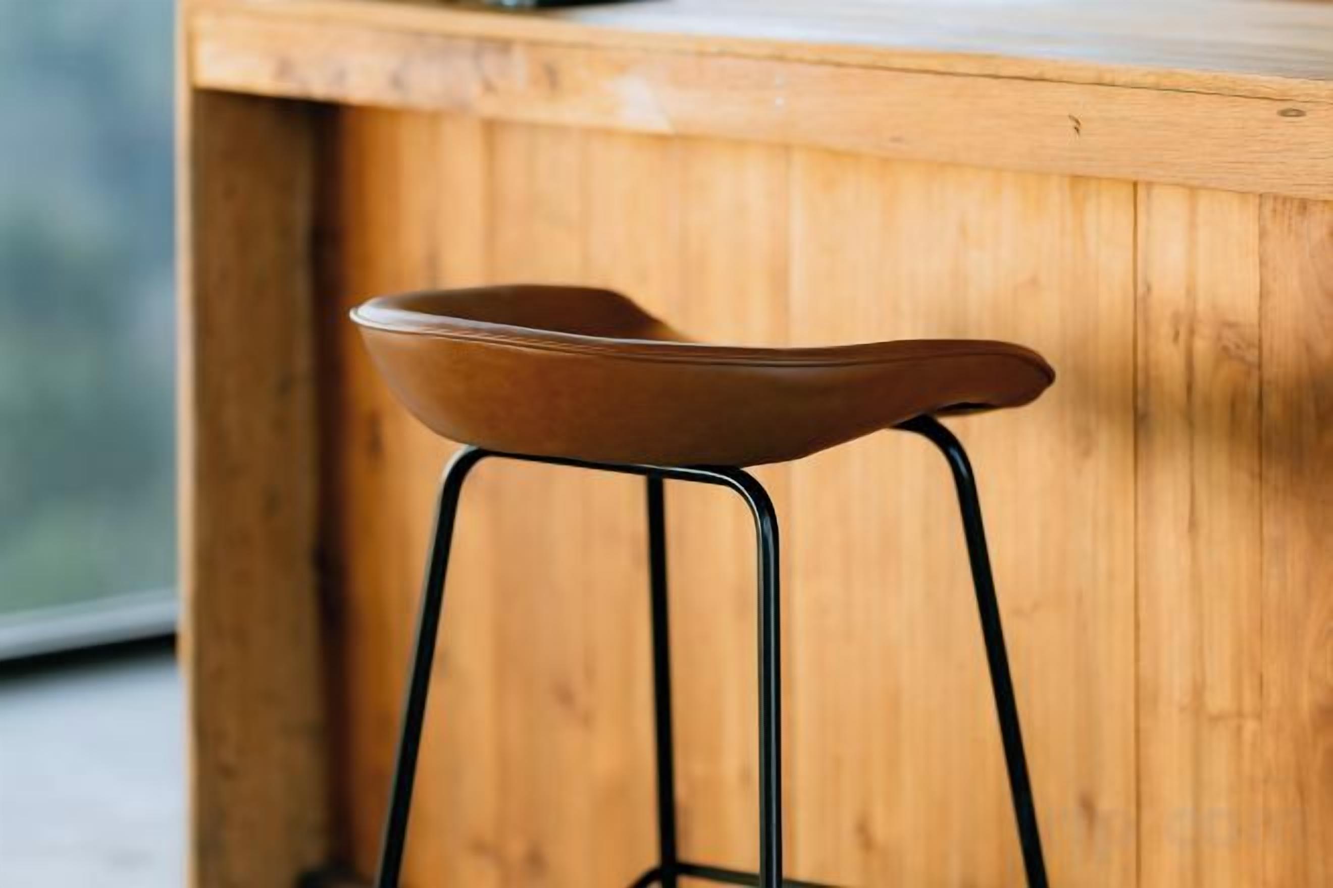 A wooden bar stool with a curved seat and metal legs.