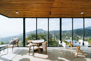 A modern interior with a wooden ceiling, large windows, and a table with chairs. - Akano Doichang (Mae Suai)