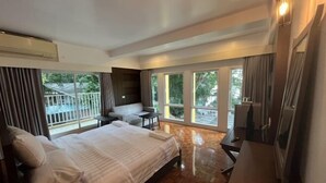 A hotel room with a bed, a desk, a chair, and large windows. - Molecular cloud (Pattaya)