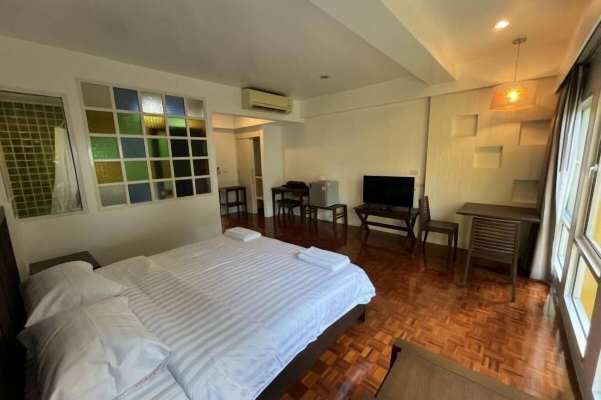 A hotel room with a bed, a desk, a TV, and a window with a view.