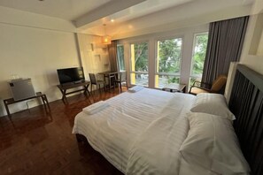 A hotel room with a large bed, a TV, a desk, and a view of the outdoors. - Molecular cloud (Pattaya)