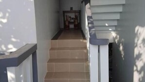 A narrow hallway with a tiled floor leading to a door at the end. - Bahai Jujai Baler by RedDoorz (Baler)