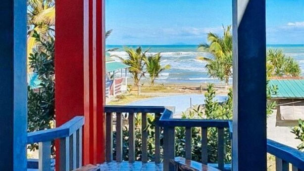 A balcony with a view of the ocean and palm trees. - Bahai Jujai Baler by RedDoorz (Baler)