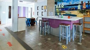 A bar area with a beach-themed mural, bar stools, and a counter. - Bahai Jujai Baler by RedDoorz (Baler)
