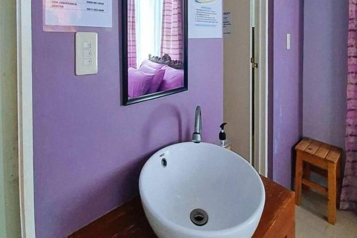 Un baño con un lavamanos blanco, un espejo y un taburete de madera.