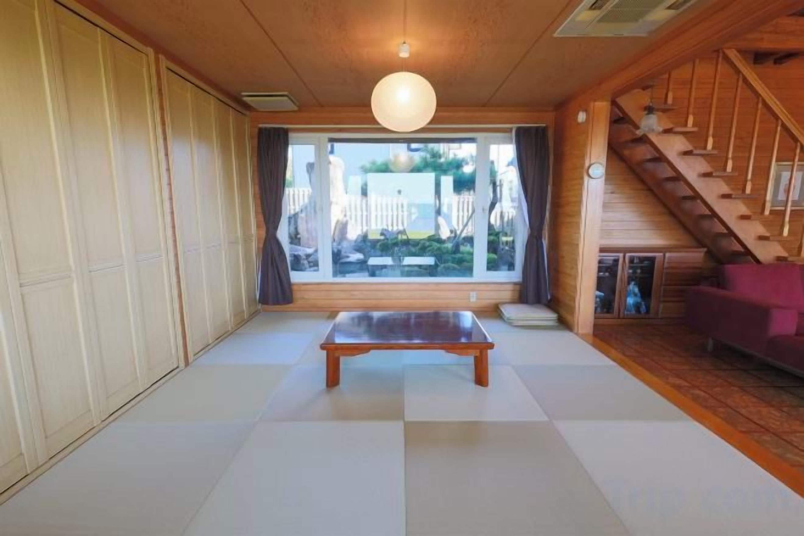 A room with tatami flooring, a wooden bench, a purple sofa, and a staircase.
