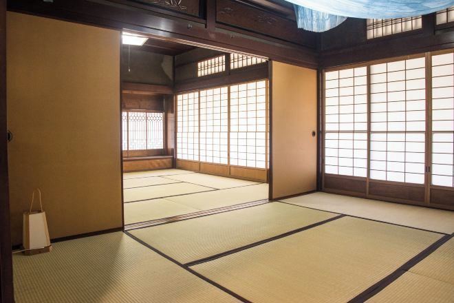 Una habitación tradicional japonesa con suelo de tatami, puertas correderas y vistas a través de las ventanas.