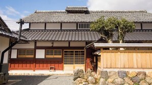 A traditional Japanese building with a tiled roof, wooden doors, and a stone wall.