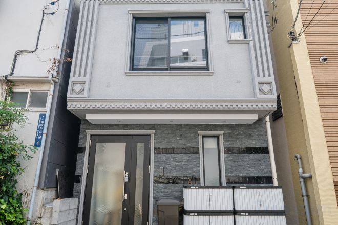 Ein zweistöckiges Gebäude mit einer Haustür, einem Fenster und einem kleinen Balkon.