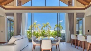 A spacious living area with a glass dining table, comfortable seating, and a view of palm trees. - The Ozon Bangtao 3-bedrooms Villas with pool by My Home Phuket (Phuket)