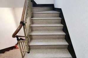 A staircase with a wooden handrail and black steps. - jeni's house (Seoul)