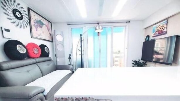 A modern living room with a grey sofa, a white coffee table, and a large window with curtains. - jeni's house (Seoul)