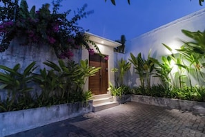 A modern house with a paved entrance, a wooden door, and lush greenery. - Villa Leaf Sanur by BaliSuperHost (Bali)
