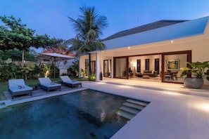 Une maison moderne dotée d’une piscine, d’un espace salon extérieur et d’un jardin bien entretenu.