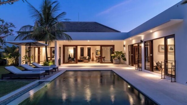 A modern house with a swimming pool, large windows, and a well-lit interior.