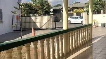 A covered outdoor area with a tiled floor, a railing, and a gated entrance.