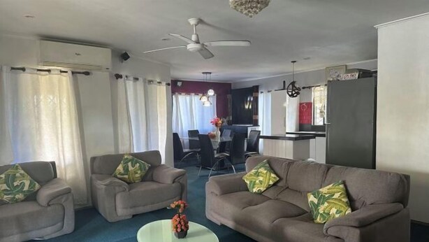 A living room with two sofas, a coffee table, and a ceiling fan. - Ac airport apartment (Nadi)