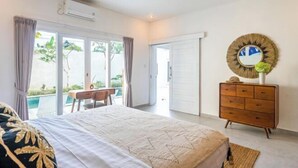 A bedroom with a bed, a dresser, a desk, and a view of the outdoors. - Villa Casa Antonio (Bali)