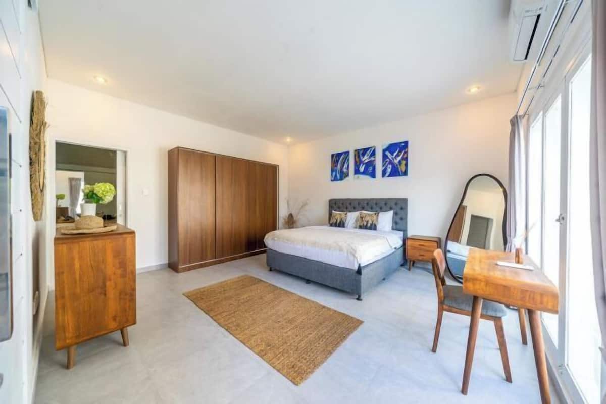 Un dormitorio con cama, armario de madera, mesita de noche y espejo.