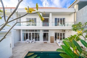 A two-story house with a balcony, a swimming pool, and outdoor seating. - Villa Casa Antonio (Bali)
