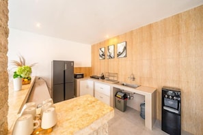 A modern kitchen with a marble countertop, black appliances, and a wooden backsplash. - Villa Casa Antonio (Bali)