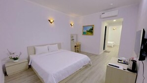 Ein Hotelzimmer mit Bett, Nachttisch, Fernseher und Schreibtisch mit Stuhl.