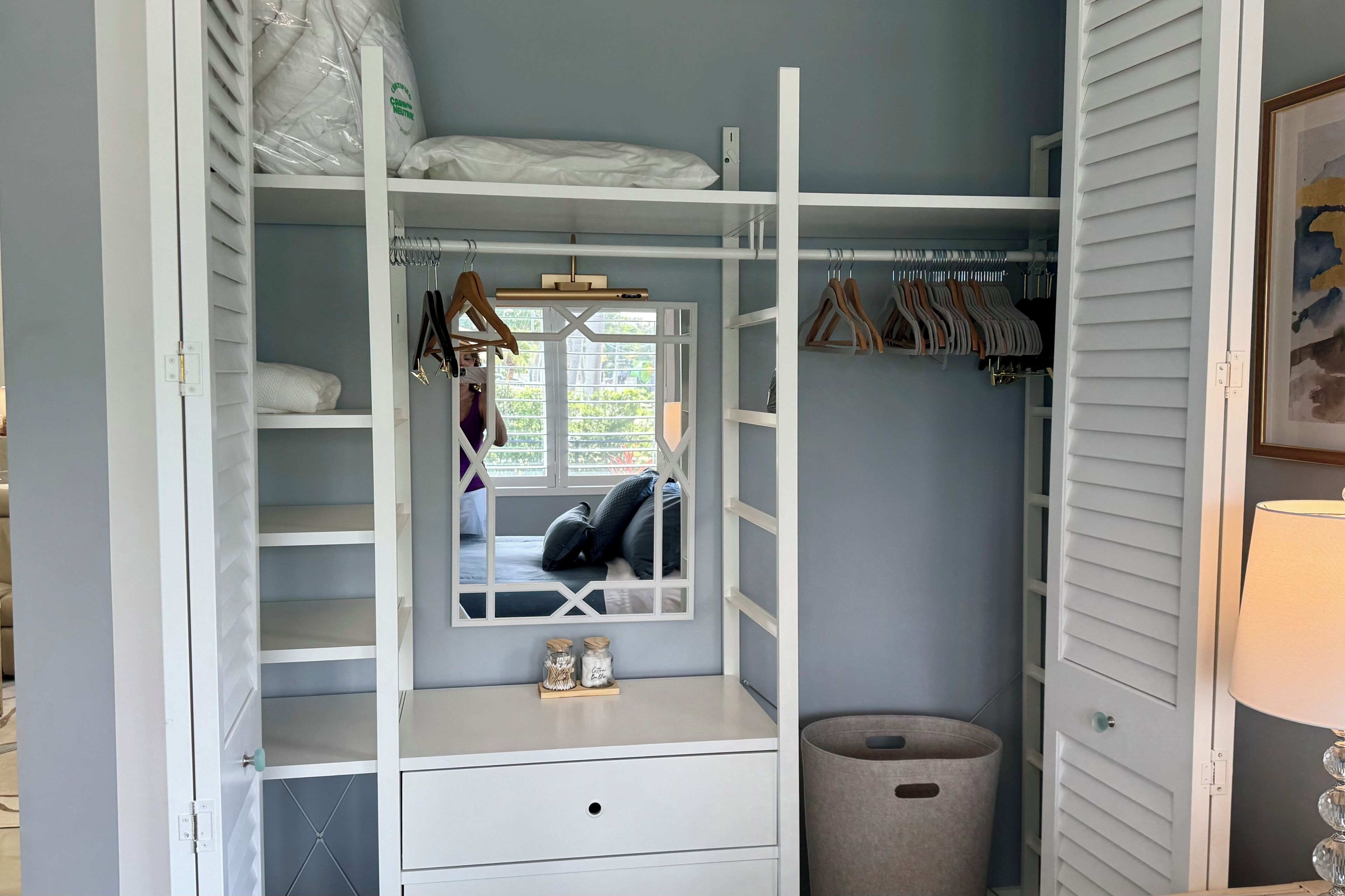 A walk-in closet with multiple shelves, hanging space, and a mirror.