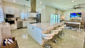 A modern kitchen with a large island, bar stools, and a ceiling fan.