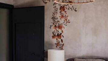 A bedroom with a bed, a hanging light fixture, a door, and a wall with a floral pattern.