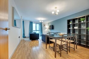 Ein modernes Hotelzimmer mit Essbereich, einer Couch, einem Fernseher und einem BĂŒcherregal.