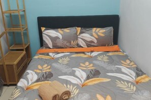 Un lit recouvert d’une couvre-lit à motifs floraux, une échelle en bois et une serviette enroulée.