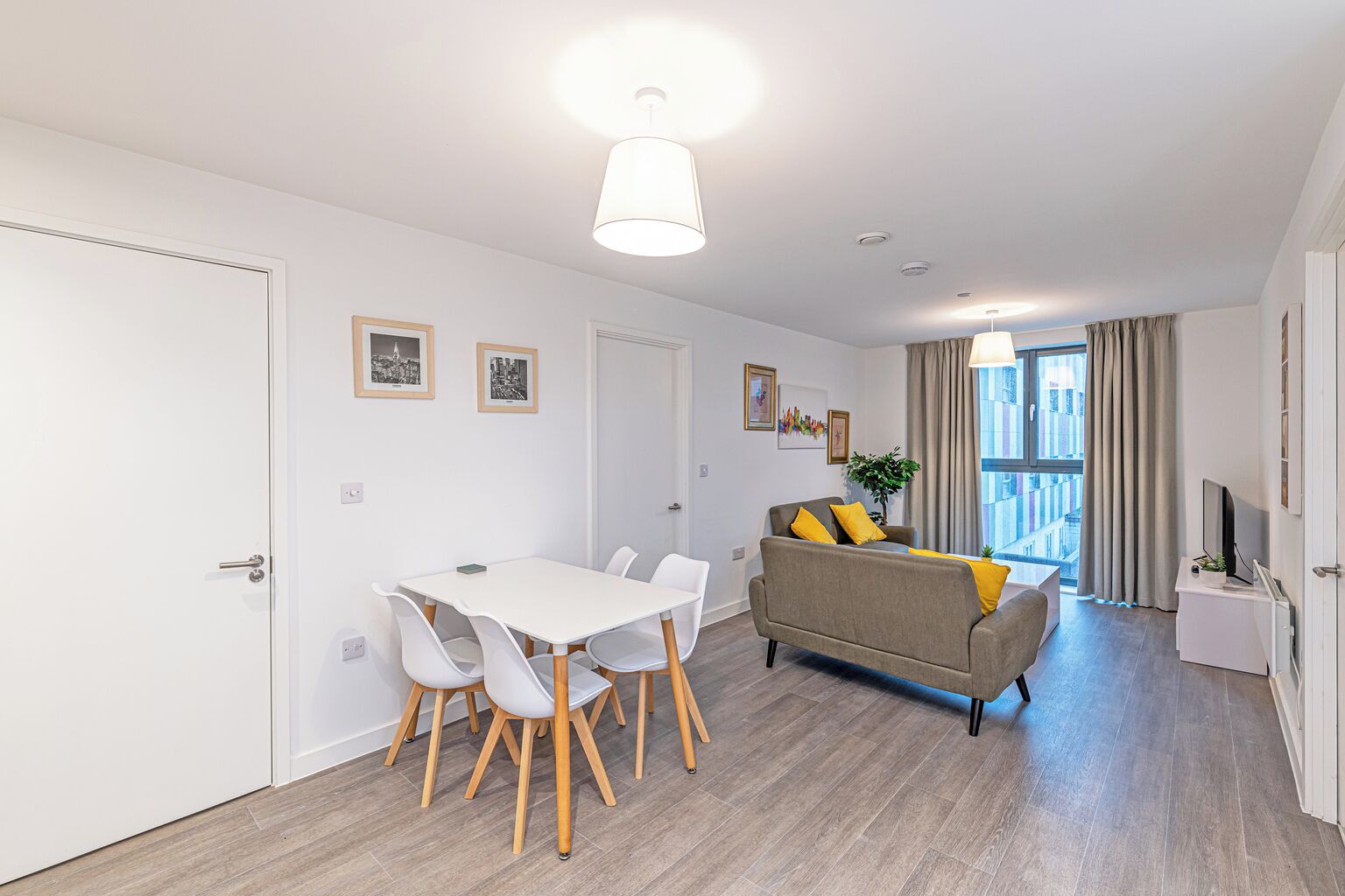 A modern apartment with a dining area, a sofa, and a TV.