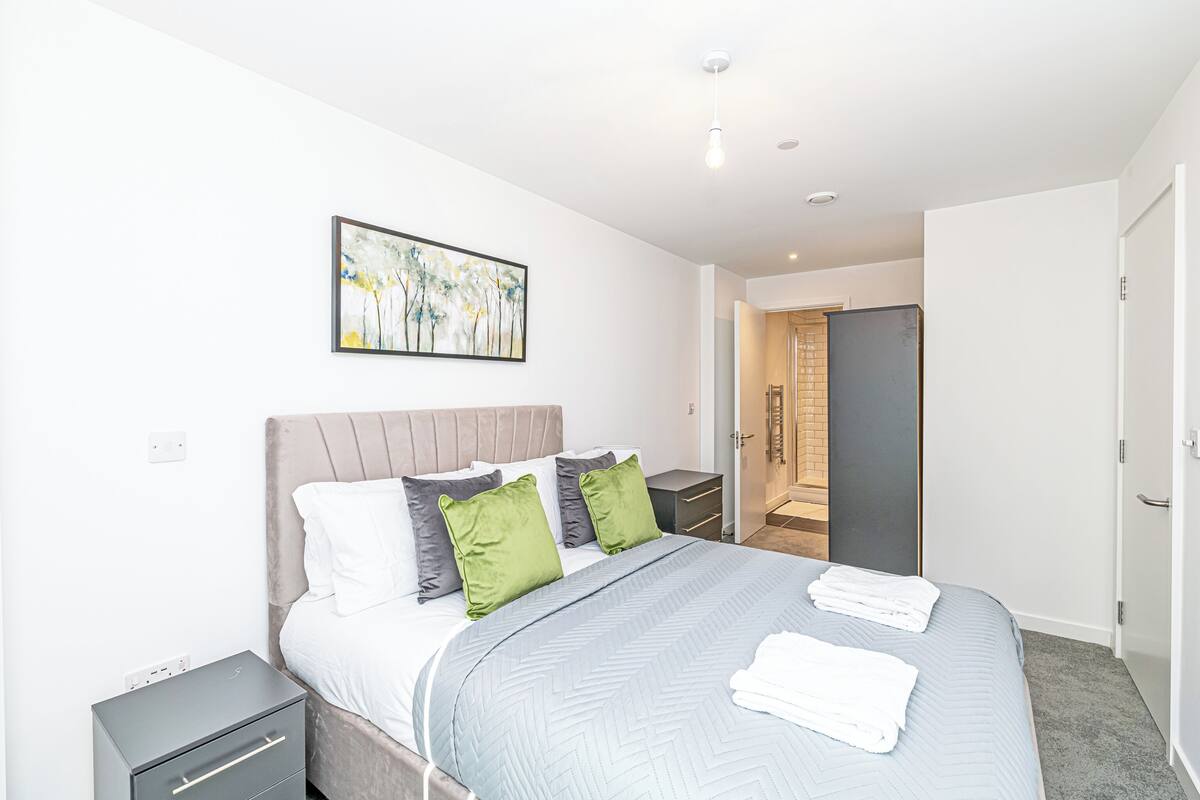 A modern bedroom with a bed, bedside tables, and a door leading to a bathroom.