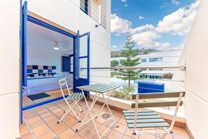 A balcony with a bed, a table, and chairs. - Villa Lucentum (Alicante)