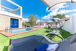 A modern outdoor pool area with a lounge chair, a small pool, and a clear sky. - Villa Lucentum (Alicante)
