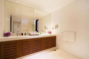 A bathroom with a large mirror, wooden cabinets, a bathtub, and a towel rack.