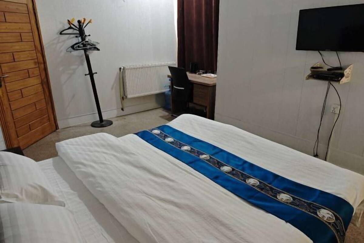 Un dormitorio con dos camas, un radiador, un escritorio y un televisor.