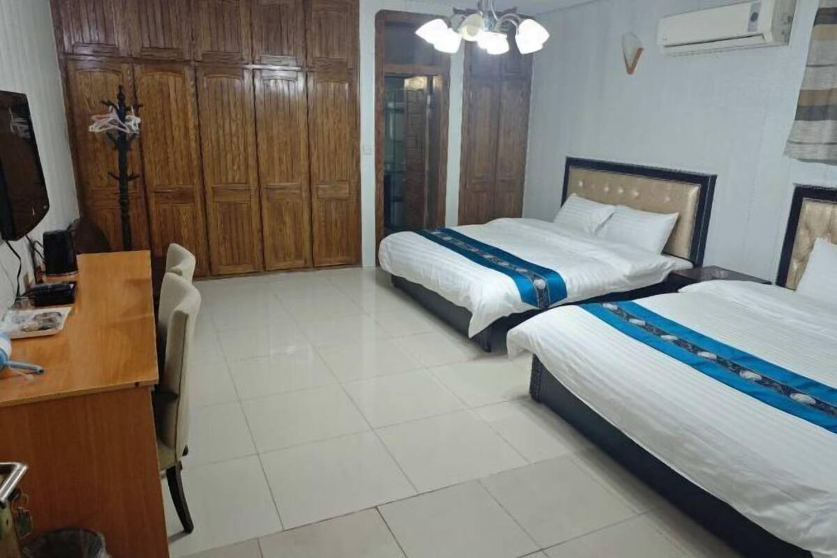 Habitaci ón de hotel con dos camas, un escritorio, una silla y armarios de madera.