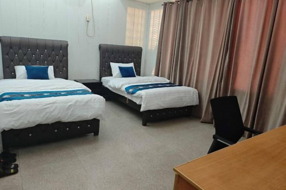 Una habitación de hotel con dos camas, un escritorio de madera y una silla.