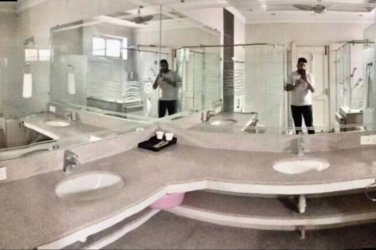 Un baño moderno con varios lavamanos, cabinas de ducha de vidrio y un espejo grande.