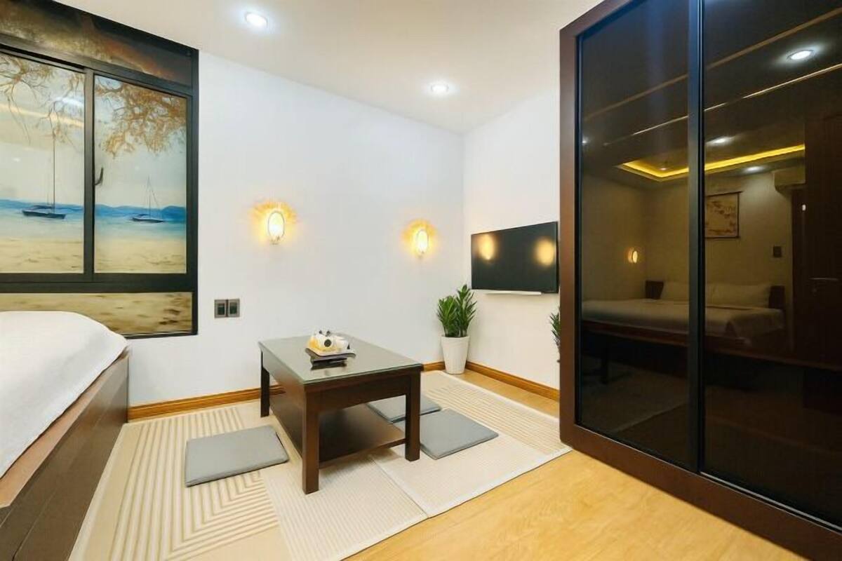 Habitación de hotel con cama, escritorio, televisor, un cuadro y puerta corredera.