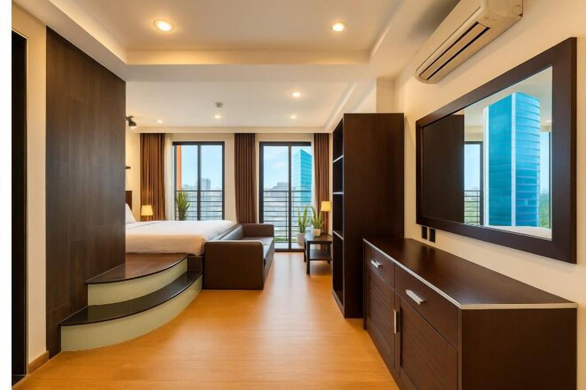 Una habitación de hotel moderna con una escalera curva, una cama, un sofá, un televisor y un ventanal con vistas a la ciudad.