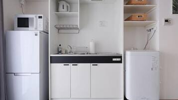 A compact kitchenette with a microwave, refrigerator, and a small fridge.