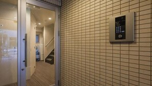 Un couloir avec une porte vitrée donnant sur une pièce, un mur recouvert de carreaux et un panneau de sécurité.
