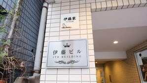 L’entrée d’un immeuble est signalée par une enseigne en japonais et en anglais, indiquant « Immeuble Ito ».